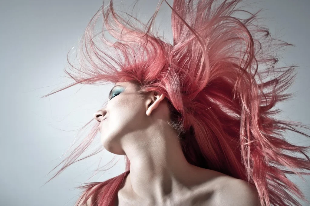 Mulher usando chapinha em cabelo cacheado para alisamento.